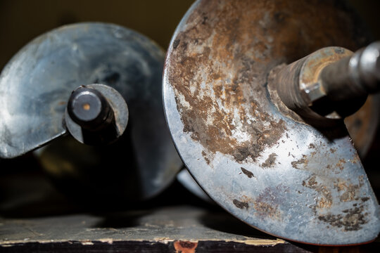 Close-up of worn metallic auger drill heads showing spiral blade texture, rust and mechanical wear used in soil drilling, construction foundation work and industrial machinery