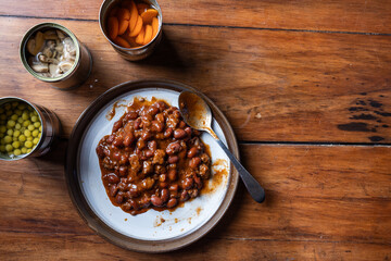 Servings of chilly and canned vegetables on a plate as a concept for National Canned Food Day.