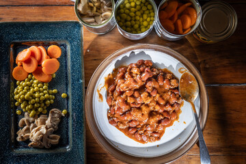 Servings of chilly and canned vegetables on a plate as a concept for National Canned Food Day.