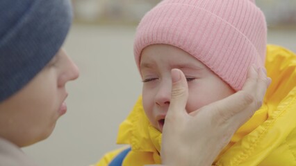 the little child is crying, bitter tears are streaming down kid cheeks, the mother calms the capricious daughter, girl is upset and roars, maternal care and care for baby, children's nervous tremors.