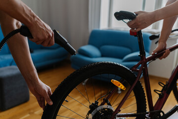 Cropped shot of two cyclists cleaning bicycle wheel using high-pressure steam cleaner, removing stubborn dirt at home, demonstrating meticulous bicycle maintenance technique. Concept of bike service