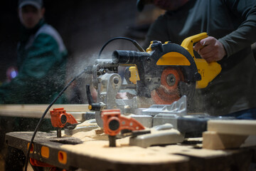A professional carpenter saws the board with a circular saw. From under the disc of the circular...