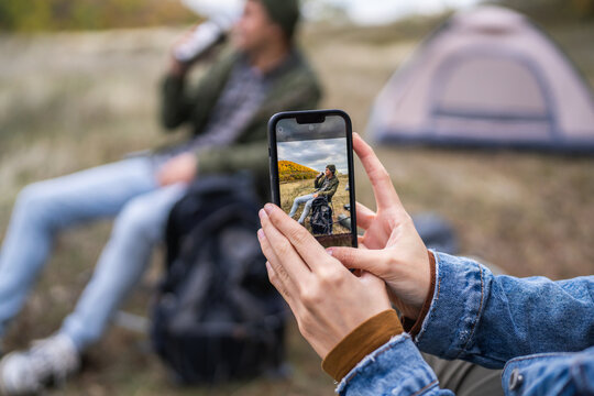 Woman capturing partner with smart phone during camping trip
