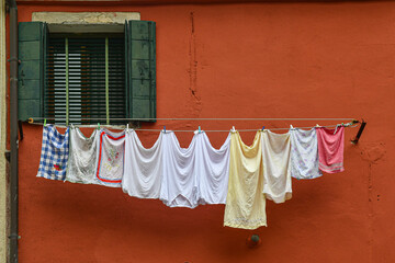Laundry hung out to dry outside the window of an old house painted orange in the historic centre of Venice, Veneto, Italy