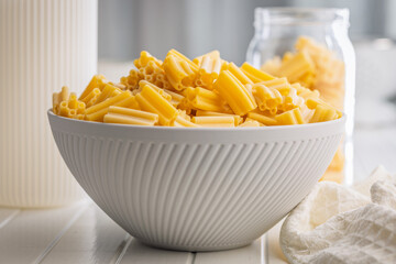 Cinque buchi. Uncooked italian pasta in bowl on white table.