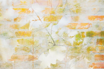 Soft abstract composition with autumn leaves and old brick wall in warm tones. Double exposure effect creates a dreamy, airy atmosphere with bright yellows and oranges.