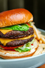 Macro of juicy double cheeseburger with lettuce and cheese. Macro shot of double cheeseburger with melted cheese, lettuce, tomato and soft bun close up.