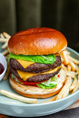 Double cheeseburger with fries and ketchup close up. Close up of juicy double cheeseburger with melted cheese, lettuce, tomato and fries on gray plate.
