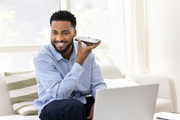 Handsome African man holds mobile phone and listens audio message