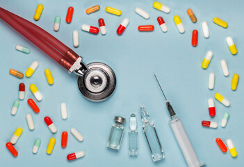 Medical pills and a phonendoscope, top view of a medical syringe and ampoules