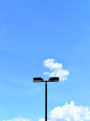 Street Light Pole on Clear Blue Sky with Fluffy White Clouds in Minimal and Urban Style, Low Angle View with Copy Space