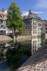 Fototapeta premium Strasbourg, France - August 26th 2025 : View of the Tanner's Quarter with half-timbered buildings and the Ill river and reflections on the water.