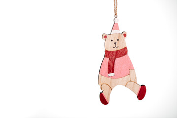 Wooden Christmas ornament shaped like a bear in a red scarf and hat on white background.
