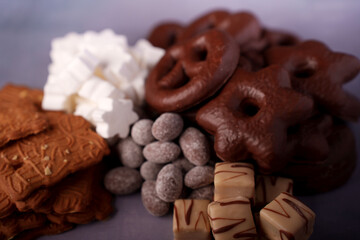 a tempting array of chocolate-coated pretzels, sugary confections, and spiced cookies on a soft purple background, inviting a sense of sweet indulgence and festive delight, peppermint, brownie