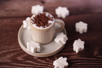 cozy cup of hot cocoa with chocolate sprinkles on wooden table surrounded by festive snowflake-shaped marshmallows in warm, inviting atmosphere, rich, topped, layered, fluffy, enjoyment, pleasure