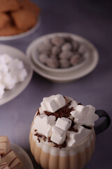 cozy hot chocolate topped with snowflake marshmallows and sprinkles amidst an assortment of sweet treats on a soft purple background, calm, serene, indoors, comfy, focus, ceramic, festive, delicious