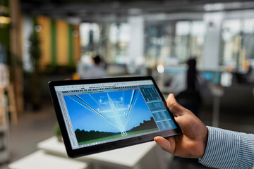 Close up of engineer using tablet to refine transmission tower systems, improving renewable energy...