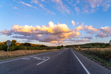 Naklejka premium Empty road under a dramatic sunset sky with clouds.