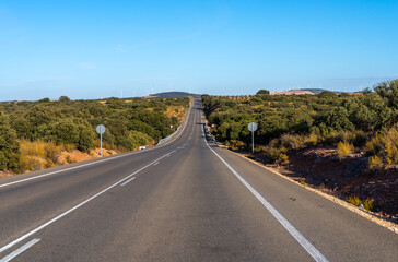 Obraz premium Empty road winds through arid landscape with wind turbines.