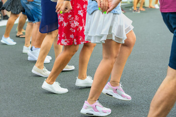 People dancing traditional Bulgarian horo on street, moving rhythmically in line with lively steps,...
