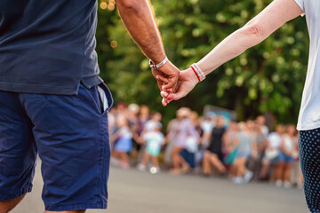 Close-up of couple holding hands during traditional Bulgarian horo dance at public event. Concept of unity in culture, Bulgarian tradition, emotional connection, national folk dance