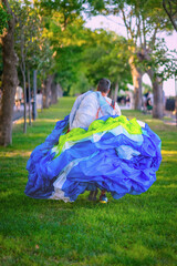 Man walking on green grass carrying colorful paragliding parachute in summer park. Concept of adventure lifestyle, extreme hobby, air sports, freedom and movement