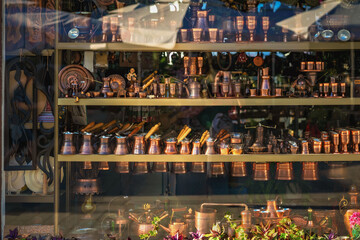 Traditional Turkish cezves and ibriks displayed in shop window alongside copper coffee sets. Concept of oriental coffee culture, handmade cezve, Turkish coffee tradition, oriental craftsmanship