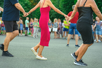 People holding hands dancing traditional Bulgarian horo in circle during public street event. Concept of cultural identity, Bulgarian folklore, Balkan unity