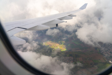 View from airplane window over clouds and landscape.