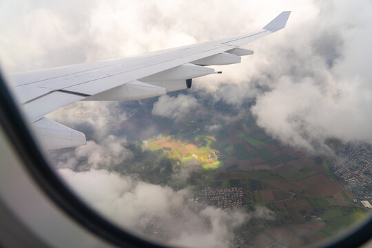 View from airplane window over clouds and landscape.