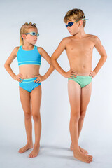 Young male and female swimmers standing confidently side by side with hands on their hips looking...