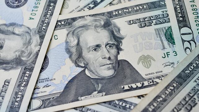 Several 20 dollar bills stacked on each other with portrait of Andrew Jackson visible. Paper currency used as legal tender for payments in domestic and international transactions 
