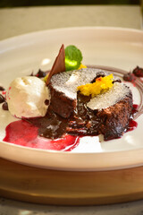 Gourmet chocolate lava brownie filled with warm melted chocolate, served with a scoop of ice cream. The rich chocolate sauce is visibly oozing from the center, creating a mouthwatering and indulgent v