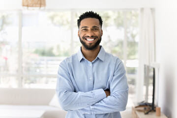 Portrait of handsome African man standing in well-lit living room