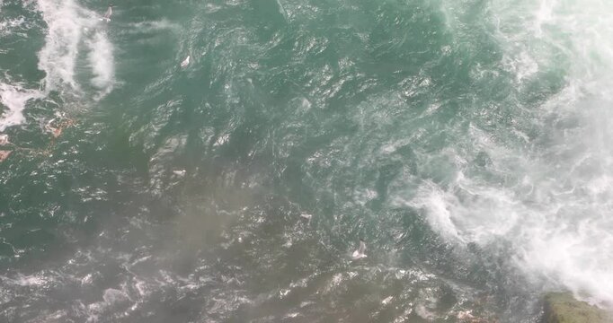 Seagulls hover and dive over churning teal water at the base of Niagara Falls, riding updrafts from the violent current and white mist. A moment of fragile survival over unstoppable force.