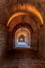 Historic brick archway corridor with warm lighting and perspective view
