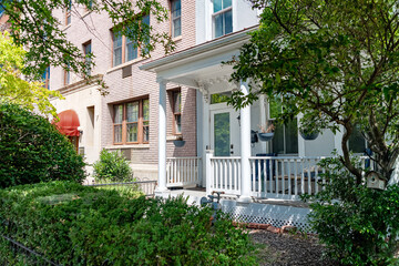 Well-maintained yard outside a classic DC home. Sunny day highlights architectural and natural beauty.