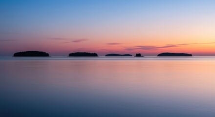 Obraz premium Tranquil seascape at dusk with small islands visible on the horizon, mirroring celestial light and the vibrant remnants of the setting sun ,environment ,serene ,peaceful