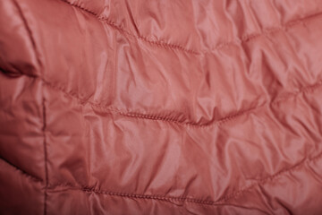 Detailed macro shot of pink padded coat surface, textile pattern and stitching design.