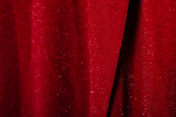 Close-up of shiny red fabric with glitter texture, elegant textile background.