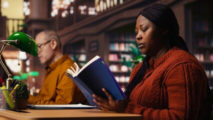 Focused woman in a study area reading and researching for master degree, reflecting the determined lifestyle of a student reaching academic and personal goals. Knowledge.