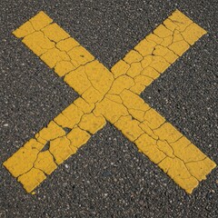 Close up view of a faded, chipped yellow X painted on a rough, deeply cracked and aged asphalt road surface texture ,deteriorated ,graphic ,aged