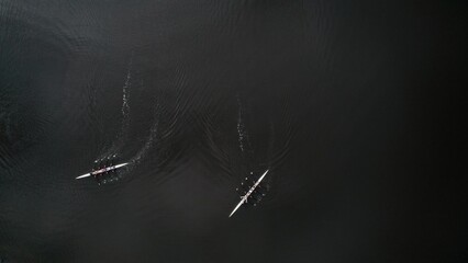 Two boats glide across the calm waters at dawn during a rowing session amidst serene surroundings