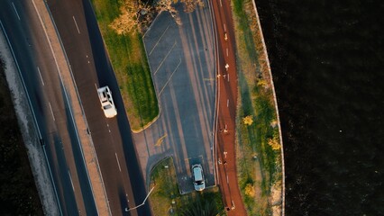 Scenic aerial view of a winding road beside a river with pedestrians enjoying a sunny day