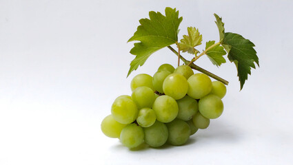 A bunch of fresh green grapes with bright leaves on a white background.