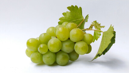 A bunch of fresh green grapes with bright leaves on a white background.