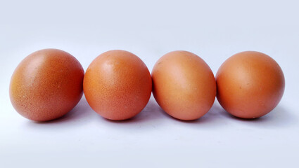 Four fresh brown chicken eggs placed on a white background.