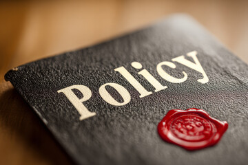 Close-up of a black policy document with embossed title and red wax seal, symbolizing authority, governance, and formal legal approval.