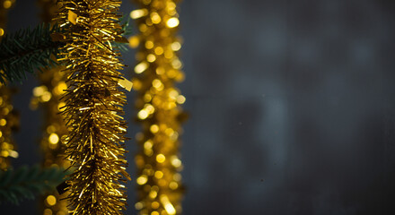 Shiny gold garland hanging against dark background, festive decoration concept