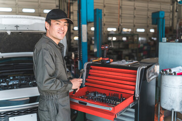A middle-aged Asian man working as a mechanic, car mechanic, or mechanic at a repair shop
